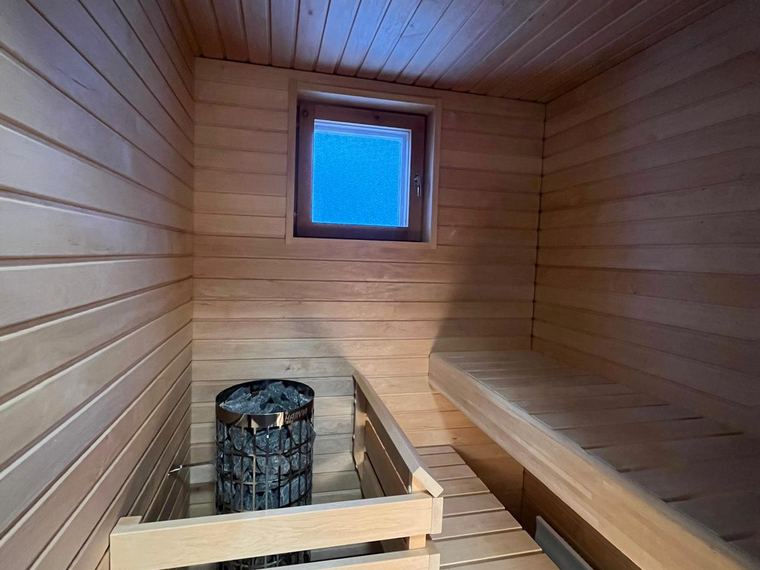 Sauna pienellä ikkunalla, lämmin puupinta ja kiuas
